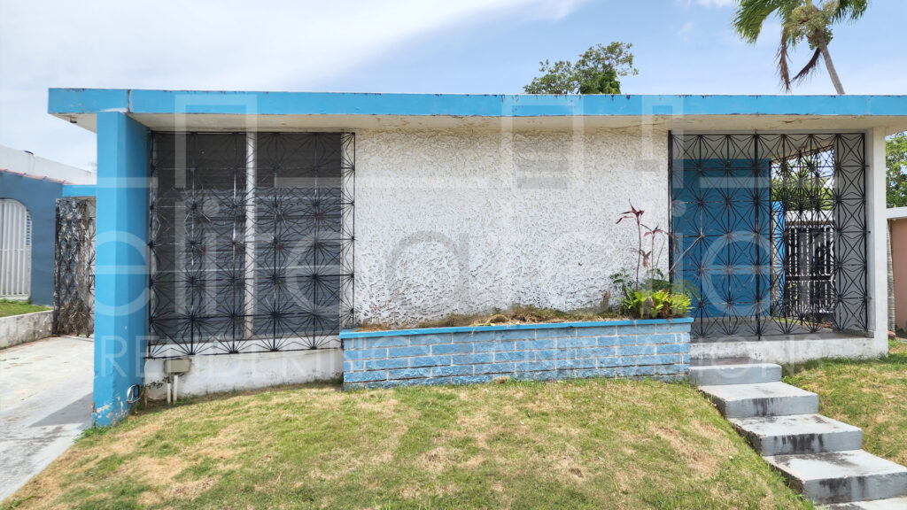Fachada residencial antes de la remodelación digital, con paredes texturizadas, detalles en azul y rejas metálicas